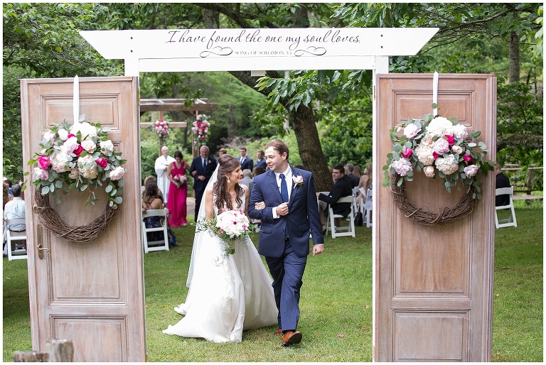 Just married and exiting through the vintage doors at outdoor ceremony.